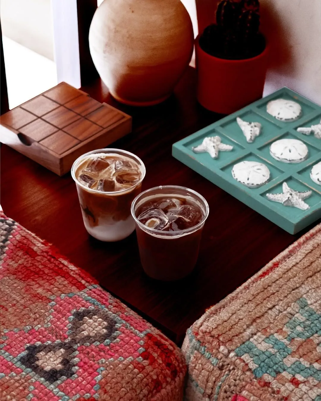 Two iced coffees, one with milk and one black, on a dark wooden table